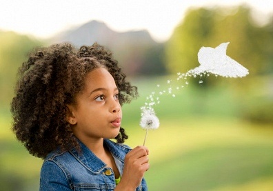 Child blowing on a flower